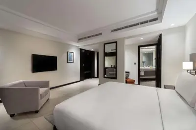 a bedroom with a bed and a chair and a television at DoubleTree by Hilton Hotel Aqaba in Aqaba