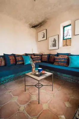 a living room with a blue couch and a table at Beit Al Fannan in Ţabaqat Faḩl