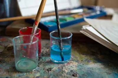 two glasses sitting on top of a table with paint at Beit Al Fannan in Ţabaqat Faḩl