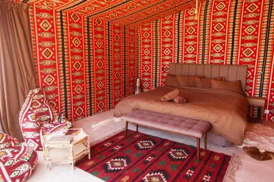 a bedroom with a bed and a bench and a rug at Arabian Nights in Wadi Rum