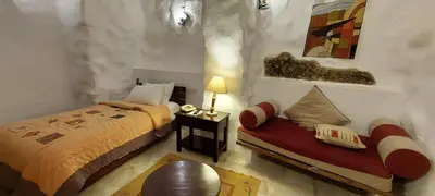 a bedroom with a bed and a bench with a lamp at Hayat Zaman Hotel And Resort Petra in Wadi Musa