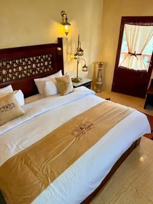 a bedroom with a large bed with white sheets and a window at Hayat Zaman Hotel And Resort Petra in Wadi Musa