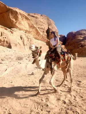a woman riding on a camel in the desert at MalakoRum in El Quweira