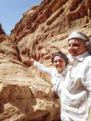a man and woman standing next to a rock wall at MalakoRum in El Quweira