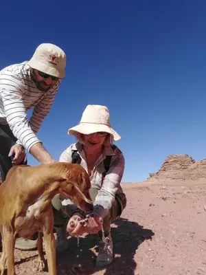 a man and a woman with a dog in the desert at MalakoRum in El Quweira