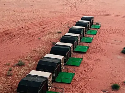 a group of green and white trucks in a field at Wadi Rum Shooting Stars Camp in Wadi Rum