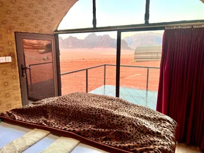 a bed in a room with a view of the desert at Wadi Rum Shooting Stars Camp in Wadi Rum