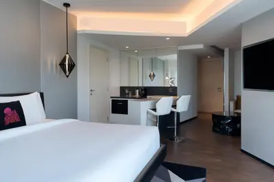 a bedroom with a white bed and a kitchen at W Amman Hotel in Amman