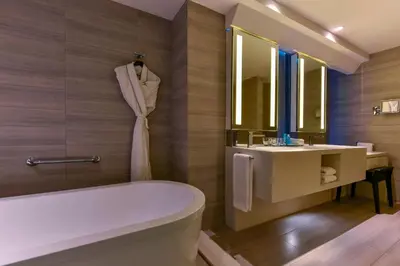 a bathroom with a tub and a sink and a mirror at W Amman Hotel in Amman