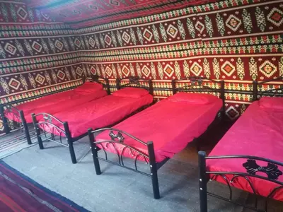 a room with four beds with red sheets at Climbers House in Wadi Rum in Wadi Rum