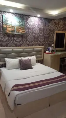 a bedroom with a large white bed with purple wallpaper at Beirut Hotel 1 in Amman