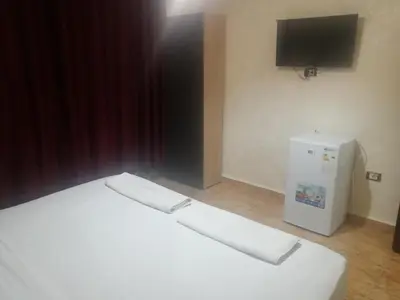a bedroom with a white bed and a television at Al-Houriat Hotel in Amman