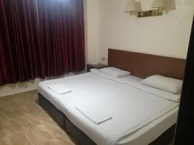 a bed in a room with a red curtain at Al-Houriat Hotel in Amman