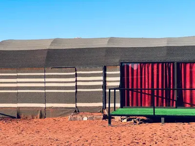a green bench sitting in front of a building at Bedouin Lifestyle Camp in Wadi Rum