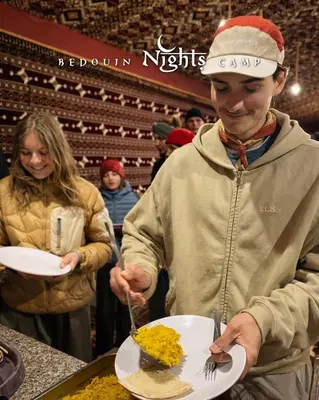 a man holding a plate of food on a table at Bedouin Nights Camp in Wadi Rum
