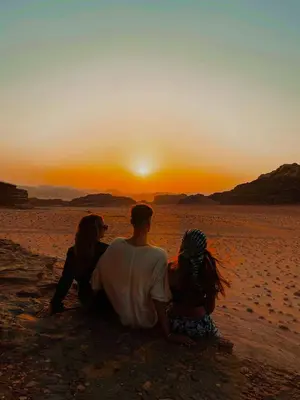 a group of people sitting on the beach watching the sunset at Bedouin Nights Camp in Wadi Rum