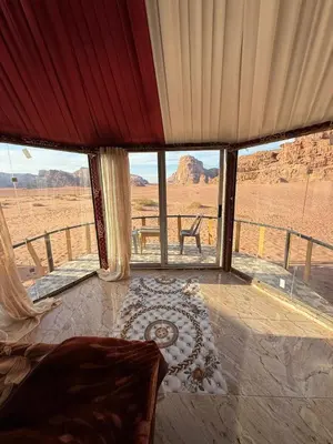 a bedroom with a view of the desert through windows at Joy to Wadi Rum in Wadi Rum