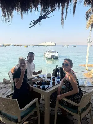 a group of people sitting at a table by the water at Al-Amer Aqaba Beach Hostel in Aqaba