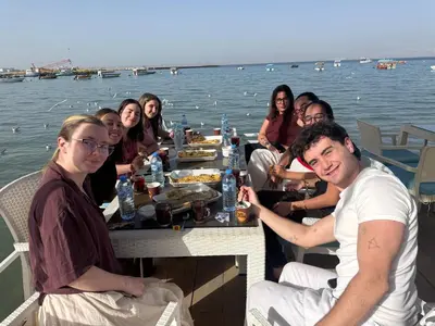 a group of people sitting around a table on the water at Al-Amer Aqaba Beach Hostel in Aqaba