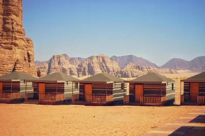 a row of houses in the desert with mountains in the background at Salman Zwaidh Camp in Wadi Rum