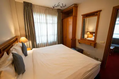 a hotel room with a white bed and a mirror at Kindi Suite Hotel in Amman