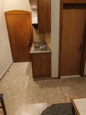 a small kitchen with a sink and wooden cabinets at Kindi Suite Hotel in Amman