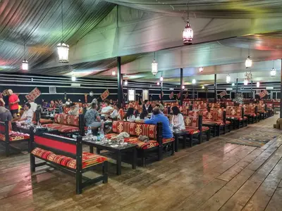 a group of people sitting at tables in a restaurant at Mazayen Rum Camp in Wadi Rum
