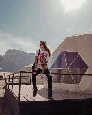 a woman sitting on a fence in front of a yurt at Mazayen Rum Camp in Wadi Rum