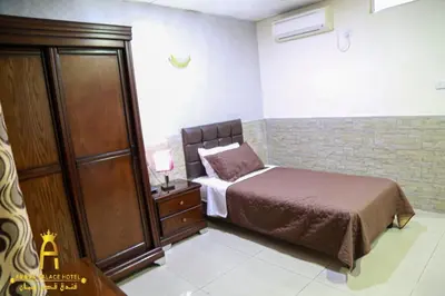 a small bedroom with a bed and a dresser at Amman Palace Hotel in Amman