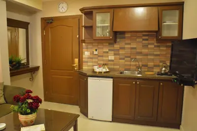 a kitchen with brown cabinets and a sink and a table at Capri Hotel Suites in Amman