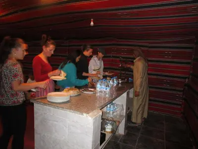 a group of people standing around a table with food at Bedouin House Camp in Wadi Rum