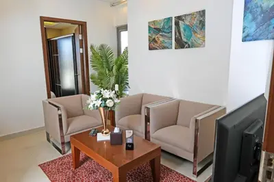 a living room with two chairs and a tv at Lijam Hotel in Amman