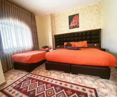 a bedroom with two beds with orange covers and a rug at Anbat Midtown Hotel in Wadi Musa