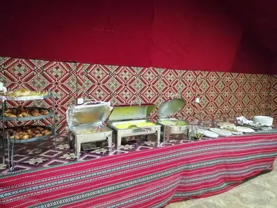a table with chairs and food on a red wall at Black Irish Camp And Tours in Wadi Rum