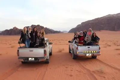 a group of people riding in the desert in a truck at Black Irish Camp And Tours in Wadi Rum