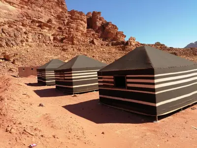 three shelters sitting in the desert near a cliff at Black Irish Camp And Tours in Wadi Rum