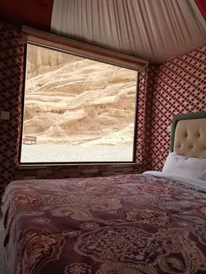 a bedroom with a view of the desert through a window at Jamal Rum desert in Wadi Rum