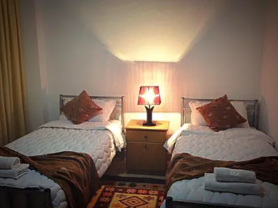 two beds in a room with a lamp on a night stand at Pilgrim's Guest House in Madaba