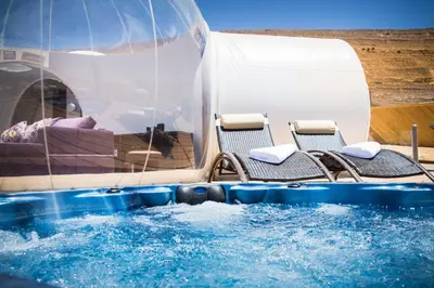 a swimming pool with two chairs in the water at Petra Bubble Luxotel in Wadi Musa