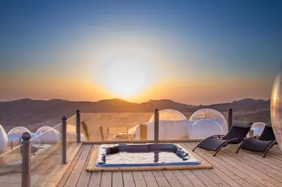 a hot tub on a deck with a view of the desert at Petra Bubble Luxotel in Wadi Musa