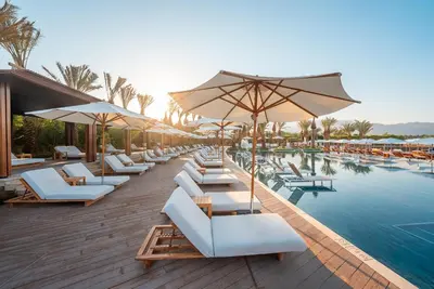 a pool with white lounge chairs and umbrellas at Hyatt Regency Aqaba Ayla Resort in Aqaba