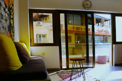 a living room with a couch and a window with a clock at Nomads Hotel in Amman