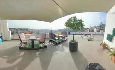 a patio with chairs and a table and a tree at Nomads Hotel in Amman