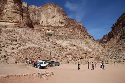 a group of people standing on a beach next to a mountain at Bedouin Expedition in Wadi Rum