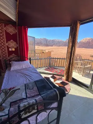 a bedroom with a bed and a view of the desert at Bedouin Holidays Camp and Jeep Tours in Wadi Rum