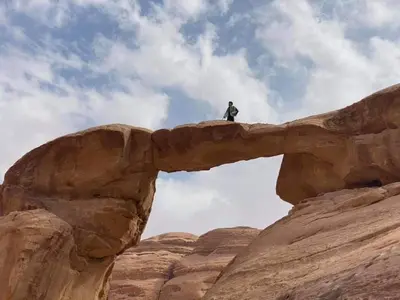 a man standing on top of a rock formation at Bedouin Holidays Camp and Jeep Tours in Wadi Rum
