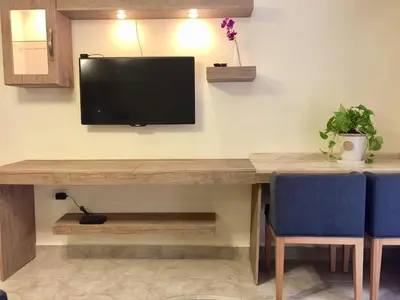 a desk with a television on a wall with two blue chairs at Royal Luxury Apartments & Studios in Amman