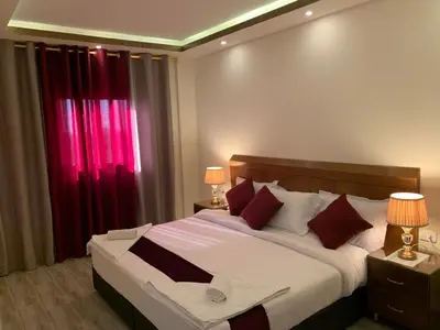 a bedroom with a large bed with red curtains at Petra Sky Hotel in Wadi Musa