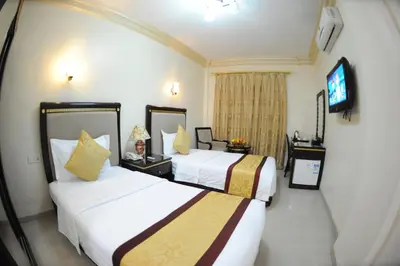 a hotel room with two beds and a tv at Cedar Hotel in Aqaba