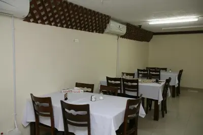 a dining room with white tables and chairs at Cedar Hotel in Aqaba
